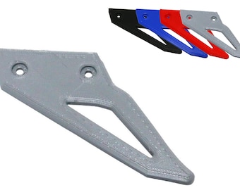 Puede incluir: Una pieza gris impresa en 3D con dos agujeros y un recorte triangular. También se muestran piezas adicionales en negro, azul, rojo y gris. Las piezas tienen un extremo puntiagudo y probablemente sean para una aplicación mecánica o estructural.