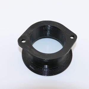 May include: A black plastic adapter with a round opening. The adapter has a smooth, slightly textured surface.