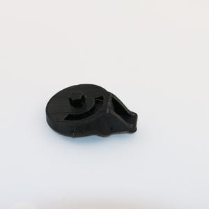 以下が含まれることがあります： 丸いベースと湾曲したアームを持つ黒いプラスチック部品。部品のベースの中央に小さな穴があります。