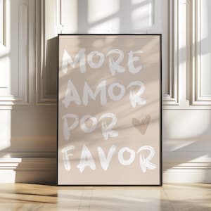 May include: A beige poster with a black frame featuring the text "More Amor Por Favor" in white brushstroke lettering with a small white heart.