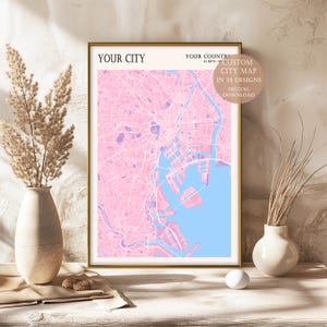 Könnte beinhalten: Ein gerahmter Druck einer benutzerdefinierten Stadtkarte in rosa und blauen Farben. Die Karte trägt den Titel "YOUR CITY" und enthält den Text "CUSTOM CITY MAP IN 24 DESIGNS DIGITAL DOWNLOAD".
