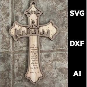 Puede incluir: Cruz de madera clara con un recorte de escena de la natividad y el texto "For unto you is born this day in the city of David, a Saviour which is Christ The Lord. Luke 2:11." La cruz tiene un borde marrón oscuro.