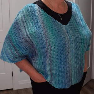 May include: A blue and green crochet top with a v-neck and short sleeves.