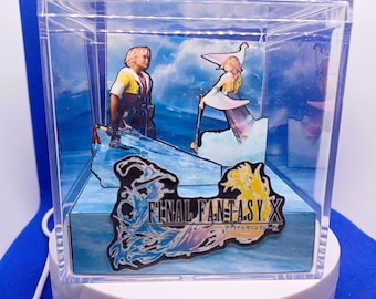 May include: A clear acrylic display box featuring a Final Fantasy X diorama. The scene depicts two characters on a blue water background with the game's logo. The box is on a white rotating base.