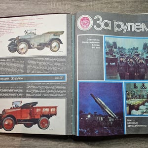 Puede incluir: Una revista vintage abierta titulada Za Rulem de febrero de 1984. La página izquierda presenta ilustraciones de un Prombron C24/45 verde claro y un camión AMO-F15 rojo. La página derecha muestra fotografías de personal militar y un lanzamisiles.