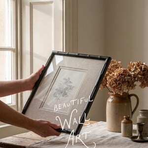 May include: A framed botanical print with a black bamboo-style frame. The print features a detailed floral illustration on a neutral linen background. The words "BEAUTIFUL WALL ART" are written on the image.