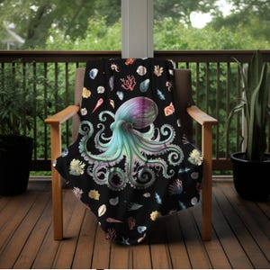 May include: A black throw blanket with a colorful octopus and seashells design. The octopus is green, blue, and purple with a white background. The seashells are various colors and shapes.