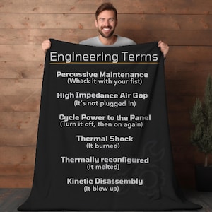 May include: A black and yellow throw blanket with the text "Engineering Terms" and a list of humorous engineering terms with definitions. The terms include "Percussive Maintenance", "High Impedance Air Gap", "Cycle Power to the Panel", "Thermal Shock", "Thermally Reconfigured", and "Kinetic Disassembly".