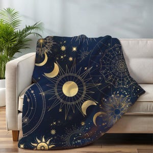 May include: A navy blue throw blanket with a gold celestial pattern featuring moons, stars, and a sun with a zodiac wheel.