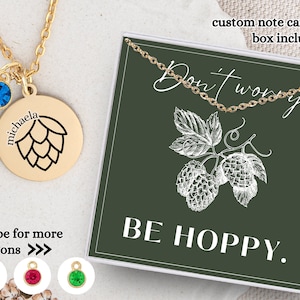 May include: Gold necklace with a hop cone charm and a blue crystal. The necklace comes in a box with a card that says "Don't worry, be hoppy."