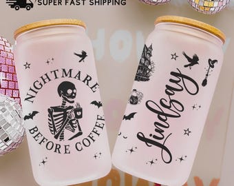 May include: Two frosted glass beverage cups with bamboo lids. One cup has a skeleton graphic with the text "Nightmare Before Coffee". The other cup has the name "Lindsay" in script. Both cups have Halloween-themed decorations.