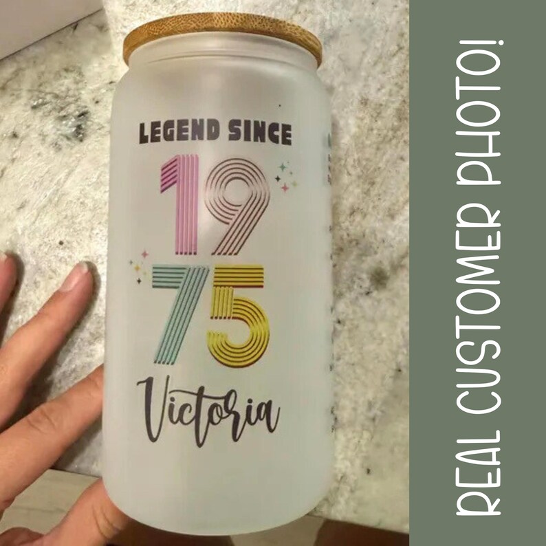 May include: Frosted glass can-shaped tumbler with a bamboo lid. The tumbler features the text "LEGEND SINCE 1975 Victoria" in various colors. The image is a customer photo.