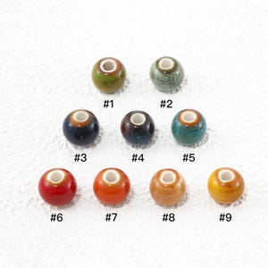 May include: Nine round ceramic beads with a central hole, each featuring a unique glaze finish. The beads are numbered #1 through #9 and display a variety of colours including green, blue, brown, red, orange, and yellow with glossy textures.