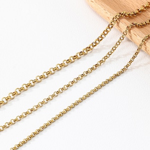 May include: A gold-toned metal chain necklace featuring a series of interconnected round links. The chain displays a consistent polished finish and a classic rolo link design, with the links arranged in a repeating circular pattern throughout the length.