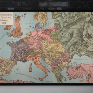 Może przedstawiać: Oprawiona, zabytkowa mapa Europy, z szczegółową ilustracją w różnych kolorach. Mapa zawiera niemiecki tekst i jest umieszczona na tle ciemnej ceglanej ściany. Ozdobne świece i wazon znajdują się na pierwszym planie.