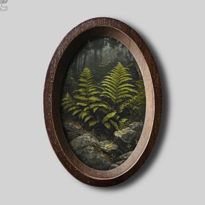 May include: An oval-shaped dark brown wooden frame containing a detailed painting of vibrant green ferns growing among grey rocks in a dark, shadowed forest setting. The artwork captures the texture of the leaves and the rugged stone surfaces.