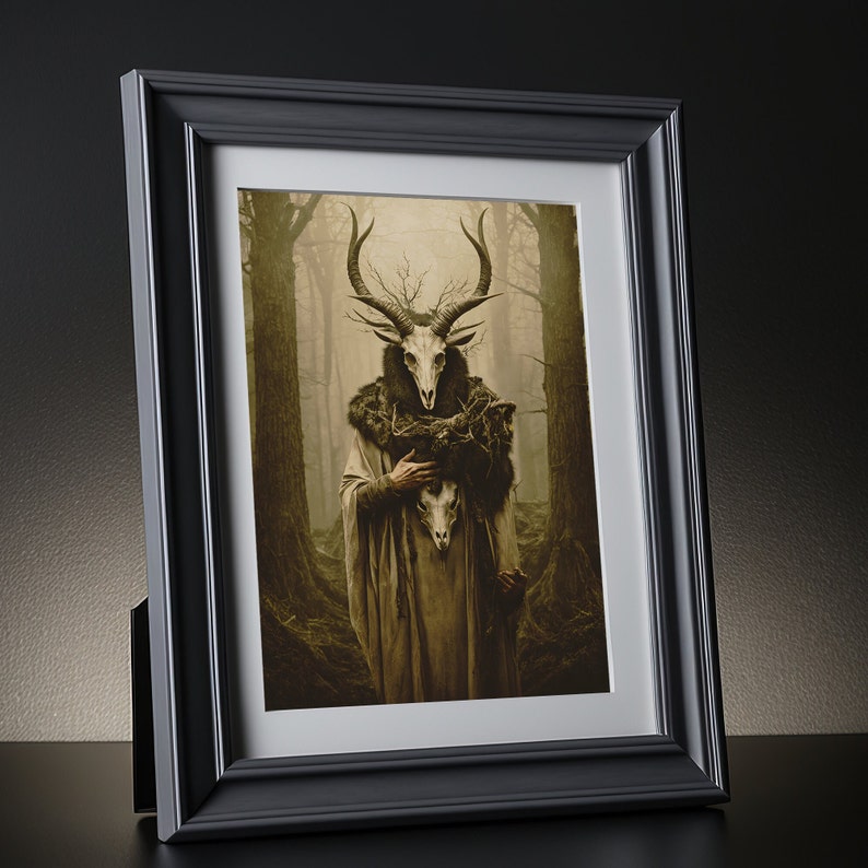 May include: Framed art print featuring a figure with a deer skull mask and antlers, set against a misty forest backdrop. The artwork has a sepia tone, and the figure wears a fur-lined cloak. The black frame adds a contrasting border to the artwork.