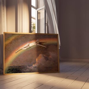 May include: A framed artwork featuring a nude figure floating through a rainbow. The painting has a warm color palette with a gold frame. The artwork is leaning against a wooden floor in a room with natural light.