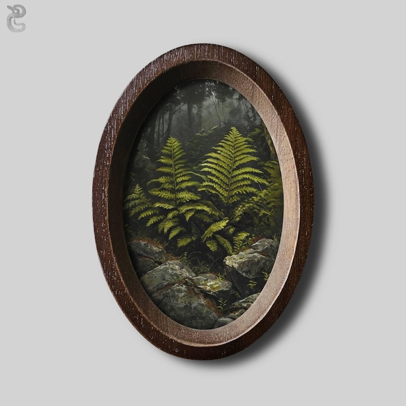 May include: An oval-shaped dark brown wooden frame containing a detailed painting of vibrant green ferns growing among grey rocks in a dark, shadowed forest setting. The artwork captures the texture of the leaves and the rugged stone surfaces.
