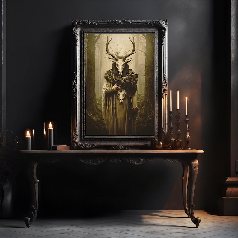 May include: A framed artwork depicts a figure with a deer skull head and antlers, wearing a long robe, set against a forest backdrop. The dark, ornate frame sits on a wooden table with lit candles and decorative candle holders, creating a gothic aesthetic.