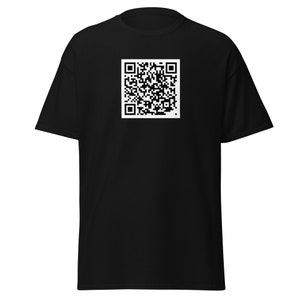 Könnte beinhalten: Schwarzes T-Shirt mit einem weißen QR-Code-Quadrat auf der Vorderseite. Das kurzärmelige Shirt ist aus einem weichen Material. Der QR-Code ist ein quadratischer Matrix-Barcode, der von einem QR-Code-Scanner gelesen werden kann.