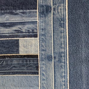Pu&ograve; includere: Primo piano di un tessuto denim patchwork. Il design presenta varie tonalit&agrave; di tessuto denim blu, cucite insieme in un motivo geometrico. Le cuciture bianche delineano le cuciture, creando una superficie strutturata e visivamente interessante.