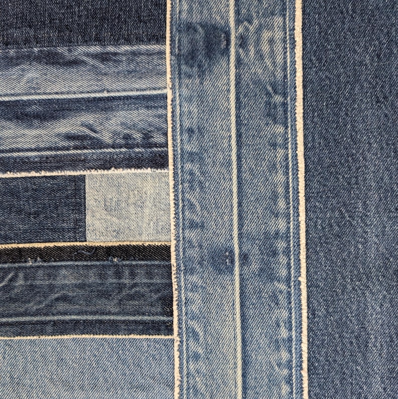 Pu&ograve; includere: Primo piano di un tessuto denim patchwork. Il design presenta varie tonalit&agrave; di tessuto denim blu, cucite insieme in un motivo geometrico. Le cuciture bianche delineano le cuciture, creando una superficie strutturata e visivamente interessante.