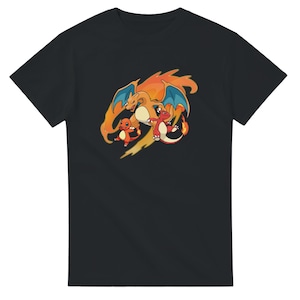 Puede incluir: Camiseta negra con un gráfico colorido de tres dragones de dibujos animados. El dragón más grande es naranja con alas azules, mientras que los más pequeños son rojos y naranjas. El diseño tiene una sensación dinámica y orientada a la acción.