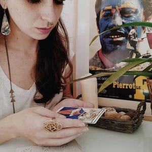 Tarot reader performing intuitive tarot reading, hands holding tarot card near candle, calm spiritual reading atmosphere