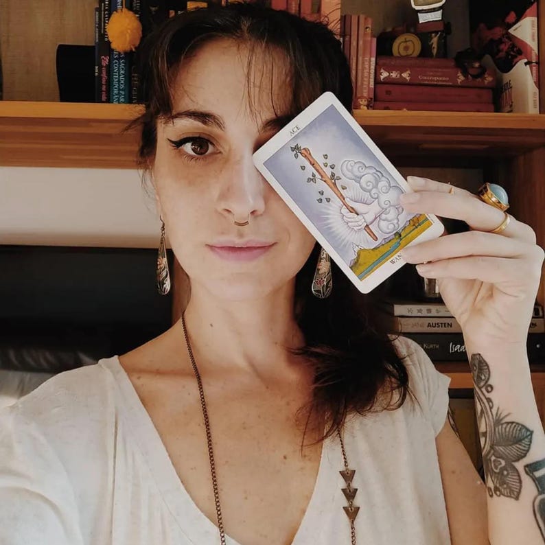Tarot reader holding Ace of Wands card, intuitive psychic guidance, tarot symbolism and spiritual insight