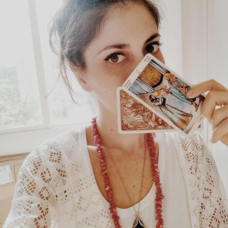 Intuitive tarot reader holding tarot cards near face, psychic insight portrait, deep spiritual connection and clarity