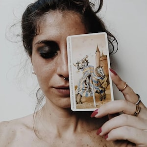 Tarot reader holding knight tarot card, shadow and truth tarot reading, deep honest psychic insight