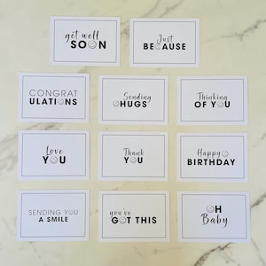 Pu&ograve; includere: Dodici carte bianche con testo nero e faccine sorridenti. Le carte hanno messaggi come "Get Well Soon", "Just Because", "Thinking of You", "Happy Birthday", "Love You", "Sending Hugs", "You've Got This", "Oh Baby", "Sending You a Smile", "Congratulations", e "Thank You".