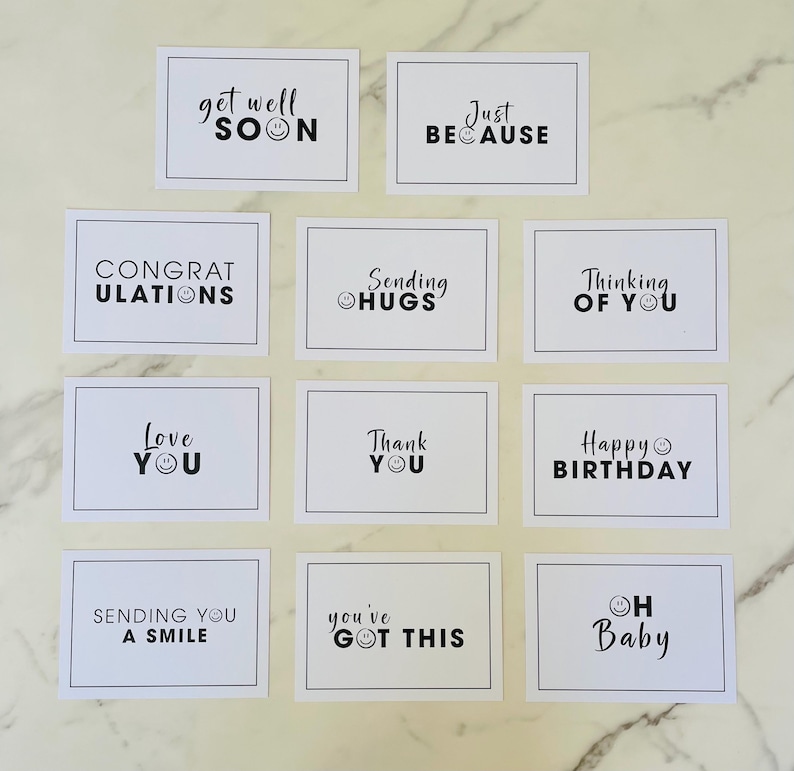 Pu&ograve; includere: Dodici carte bianche con testo nero e faccine sorridenti. Le carte hanno messaggi come "Get Well Soon", "Just Because", "Thinking of You", "Happy Birthday", "Love You", "Sending Hugs", "You've Got This", "Oh Baby", "Sending You a Smile", "Congratulations", e "Thank You".