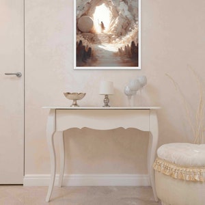 Puede incluir: Una pintura que representa la abertura de una cueva con una figura de pie en la entrada. La cueva est&aacute; hecha de piedra y la figura lleva una t&uacute;nica blanca. La pintura est&aacute; enmarcada en blanco y cuelga de una pared blanca.