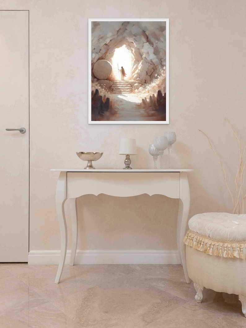 Puede incluir: Una pintura que representa la abertura de una cueva con una figura de pie en la entrada. La cueva est&aacute; hecha de piedra y la figura lleva una t&uacute;nica blanca. La pintura est&aacute; enmarcada en blanco y cuelga de una pared blanca.
