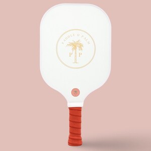 The back of a pickleball paddle with a yellow paddle and palm logo on a white background