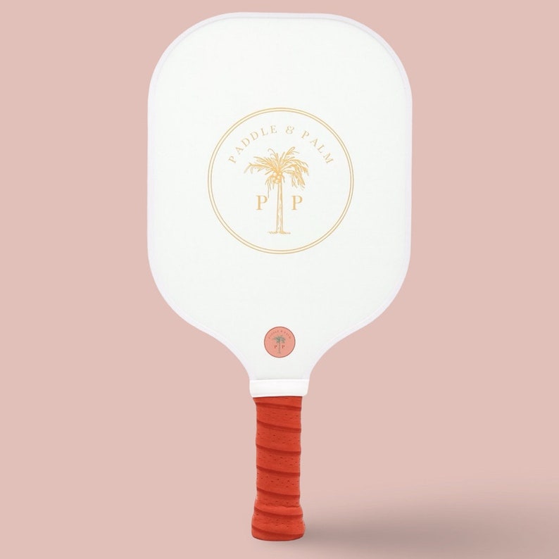 The back of a pickleball paddle with a yellow paddle and palm logo on a white background