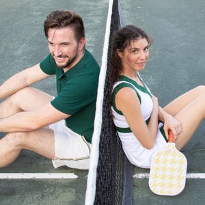 Peut inclure: Deux personnes portant des tenues de tennis vertes et blanches sont assises de chaque côté d'un filet. La personne à gauche tient une raquette. La personne à droite tient une raquette.