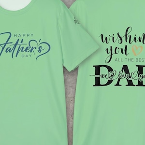 May include: Two light green t-shirts. The front of the first shirt has the text "Happy Father's Day" in blue script. The back of the second shirt says "Wishing You All The Best Dad We Love You" in black script with a heart.