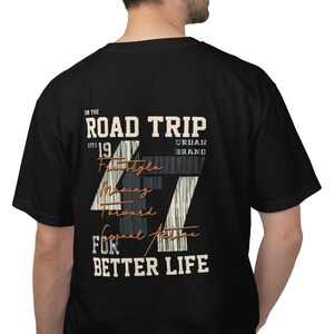 May include: A black short-sleeve t-shirt featuring a graphic on the back with the text ON THE ROAD TRIP EST 19 URBAN BRAND FOR BETTER LIFE. The design includes a large number 47 with a striped pattern and the words Freestyle Moving Forward Casual Active.