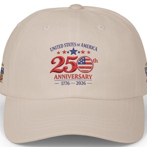 May include: A beige baseball cap with the text "UNITED STATES OF AMERICA" and "250th ANNIVERSARY 1776-2026" in red, white, and blue. The cap has a curved brim and a structured crown.