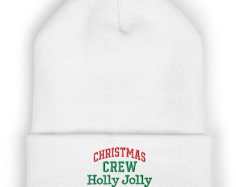 May include: A white cuffed beanie featuring embroidered text on the front. The word CHRISTMAS is stitched in red, while the words CREW and Holly Jolly are stitched in green, centered on the folded cuff of the knit hat.