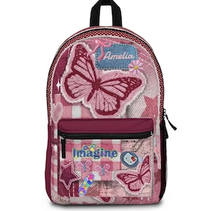 May include: A pink and maroon backpack featuring a collage of butterfly patches, a denim-style patch with the name Amelia, a star, and the word Imagine. The bag has a polka dot trim, a front zippered pocket, and a black top handle and zippers.