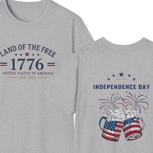 Pu&ograve; includere: Una t-shirt grigio melange con una grafica frontale con il testo LAND OF THE FREE 1776 UNITED STATES OF AMERICA EST. 1776 e una grafica sul retro che mostra due boccali di birra con motivi della bandiera americana, fuochi d'artificio e il testo HAPPY INDEPENDENCE DAY.