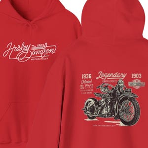 May include: A bright red hooded sweatshirt featuring a white Harley-Davidson logo on the front. The back displays a detailed black and white graphic of a 1936 motorcycle with the text Legendary, 1936 Model EL Type, and 1903 Harley-Davidson logo.