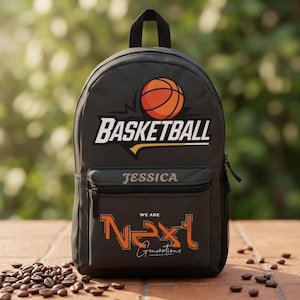 Może przedstawiać: Ciemnoszary plecak z grafiką piłki do koszyk&oacute;wki nad słowem BASKETBALL. Przednia kieszeń zawiera imię JESSICA jasną czcionką, a poniżej pomarańczowy napis WE ARE NEXT oraz słowo Generations zapisane pismem odręcznym.