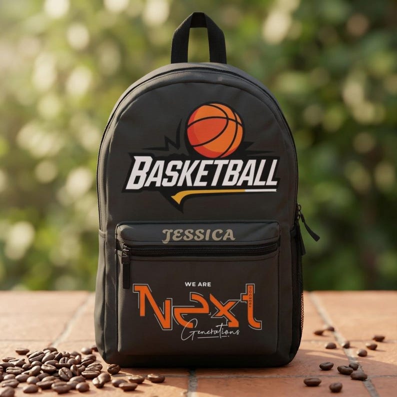 Może przedstawiać: Ciemnoszary plecak z grafiką piłki do koszyk&oacute;wki nad słowem BASKETBALL. Przednia kieszeń zawiera imię JESSICA jasną czcionką, a poniżej pomarańczowy napis WE ARE NEXT oraz słowo Generations zapisane pismem odręcznym.