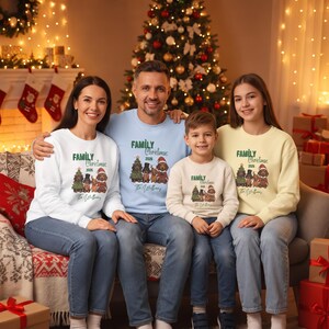 K&ouml;nnte beinhalten: Vier lang&auml;rmelige Rundhals-Sweatshirts in Wei&szlig;, Hellblau, Beige und Hellgelb. Jedes zeigt eine Grafik von vier Hunden in festlicher Kleidung, den Text "Family Christmas 2026" und den Namen "The Williams" auf der Vorderseite aufgedruckt.