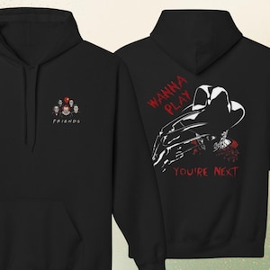 Peut inclure: Un sweat &agrave; capuche noir avec un petit motif sur la poitrine repr&eacute;sentant des personnages d'horreur et le texte FRIENDS. Le dos pr&eacute;sente un grand graphisme d'une silhouette griffue avec un chapeau et le texte rouge WANNA PLAY YOU'RE NEXT.
